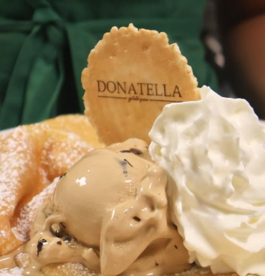 Crepe polvilhado com açúcar, com uma bola de gelado, chantilly e uma bolacha com o nome da casa